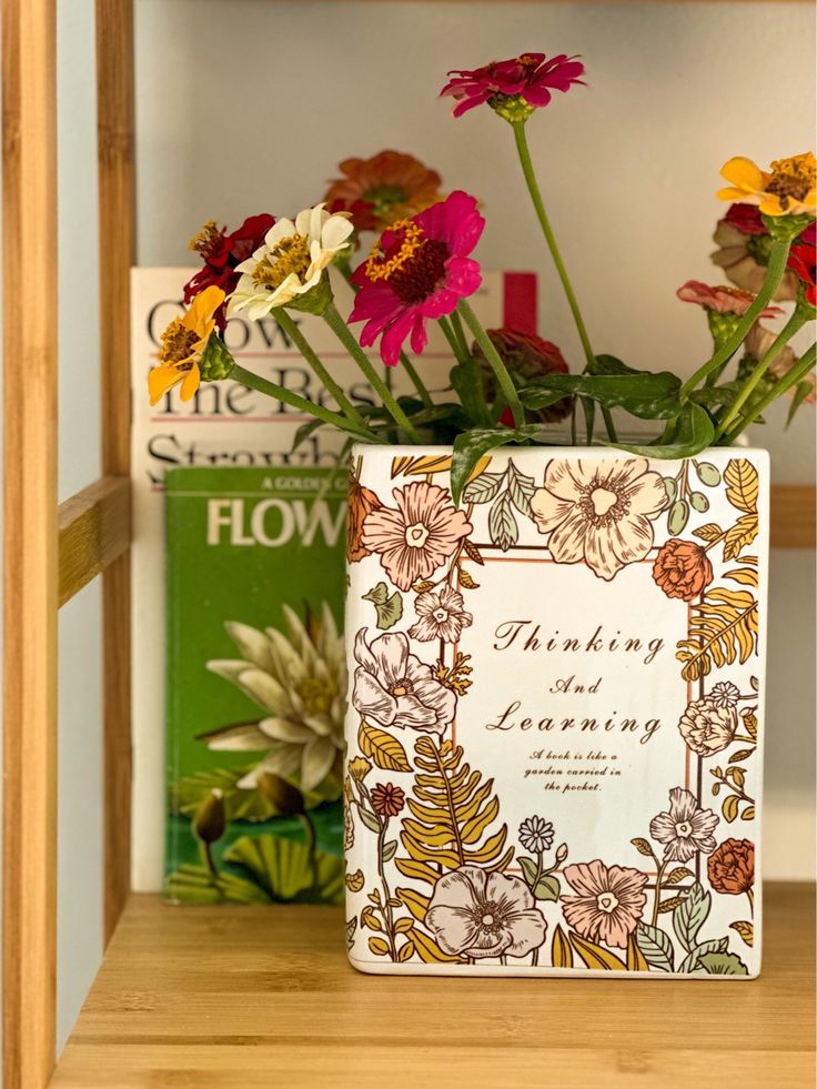 Vaso em formato de livro branco com flores na capa