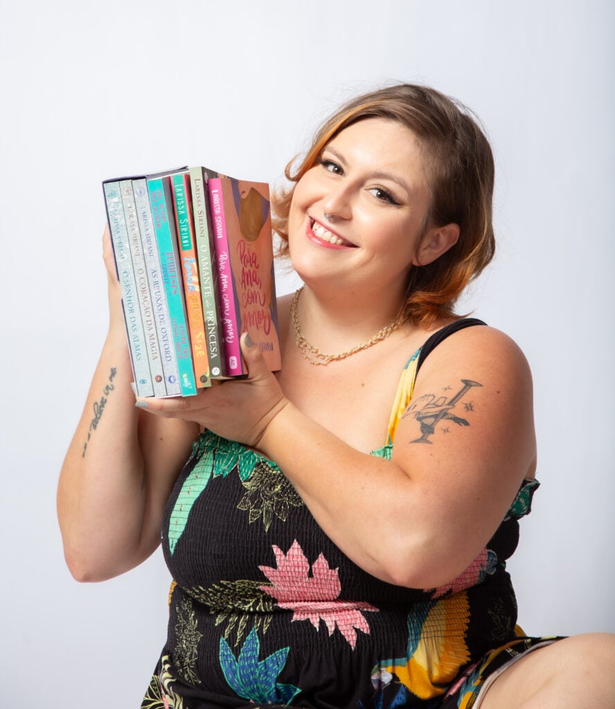 Larissa Siriani segurando livros na mão.