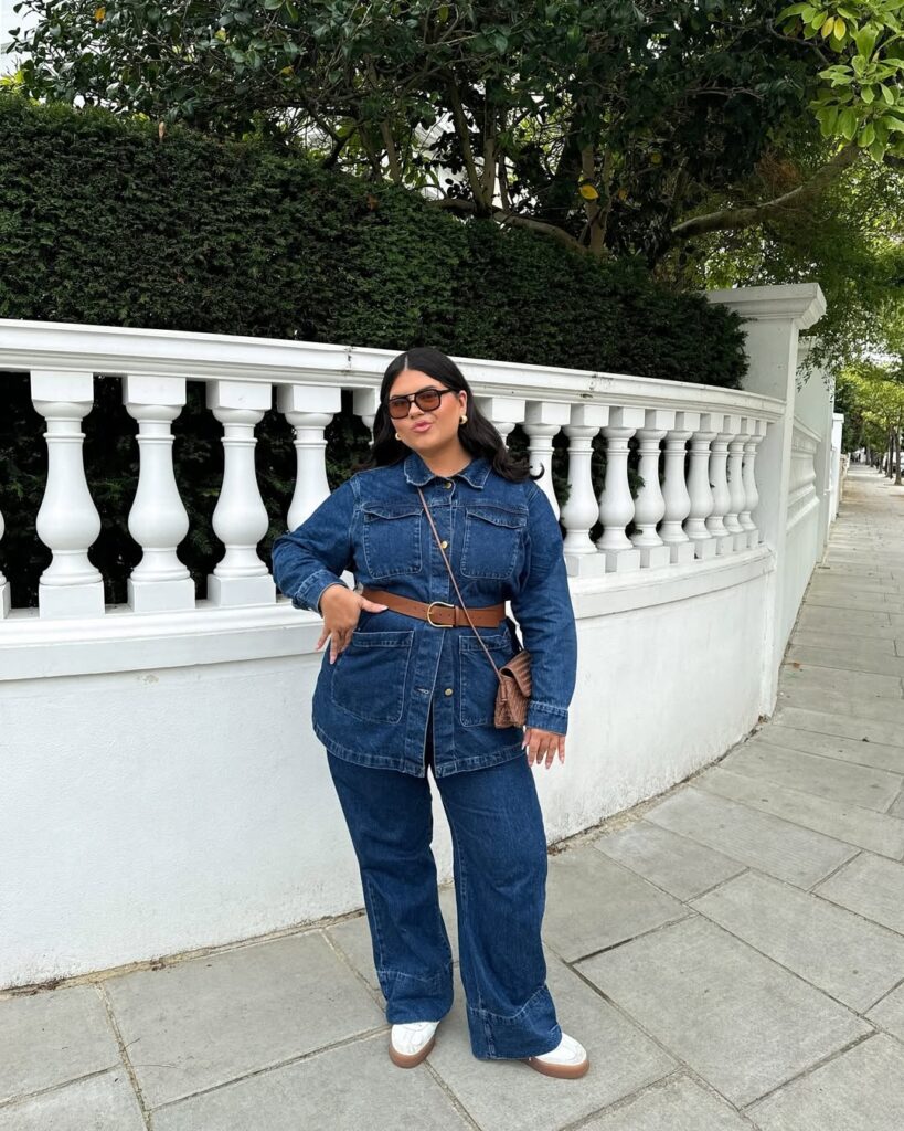 Mulher de pele clara, com look all jeans, cinto e bolsa marrom, com tênis branco
