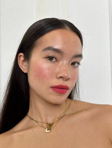 Mulher de pele clara, com cabelo escuro liso, acessórios em dourado e lábios românticos