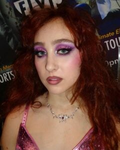 Chappell Roan, com body de alcinha rosa, cabelo ruivo e maquiagem new wave com sombra colorida