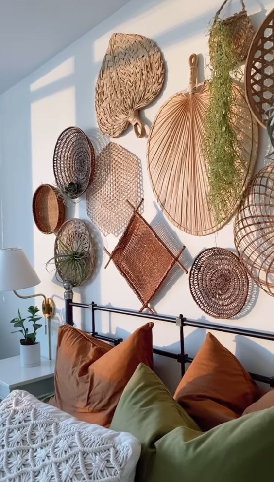 Cama de ferro com almofadas terrosas e verde com enfeites de palha na parede