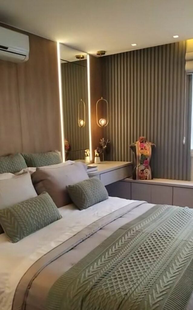 Quarto de casal com parede ripada verde, arandela e roupas de cama verde
