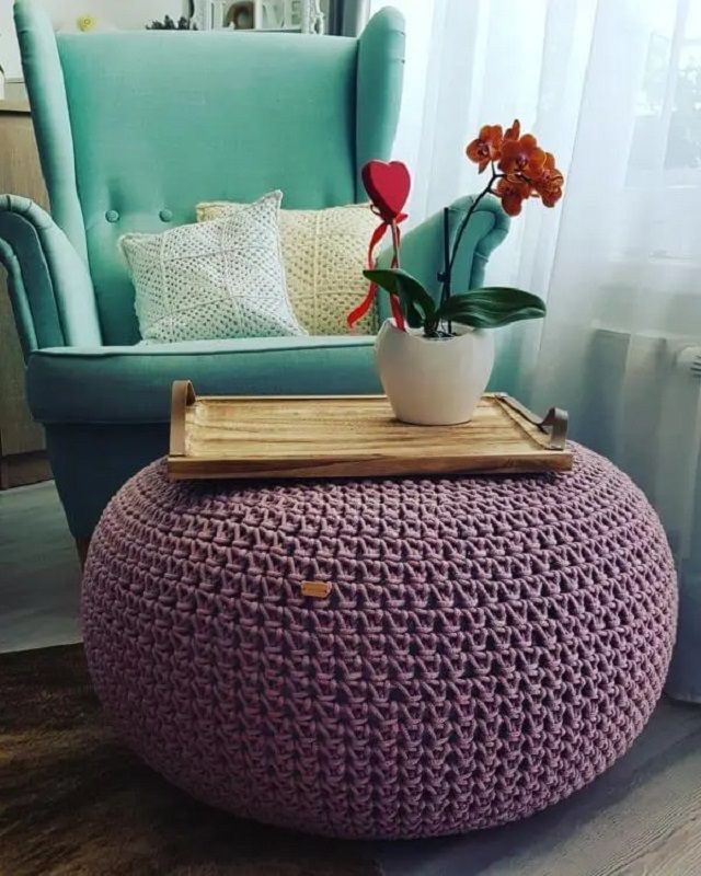 Poltrona azul com puff em crochê lilás com bandeja em madeira e vaso de flores