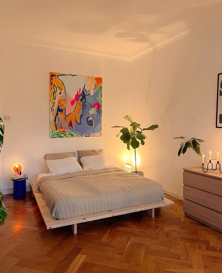 Quarto com cama sem cabeceira e com quadro na parede
