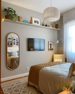 Quarto de casal com cama, tapete, passadeira, TV, espelho e prateleira