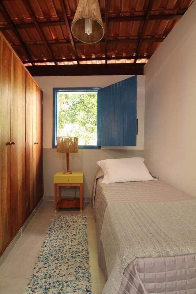 Quarto de solteiro com cama, passadeira e mesa de cabeceira