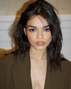 Rachel Zegler, com blazer marrom e cabelo escuro com corte gatinho