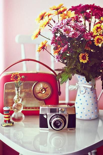 Rádio e máquina fotográfica retrô em mesa com vaso de flores