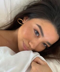 Mulher de pele clara, com cabelo preto e acessórios em dourado