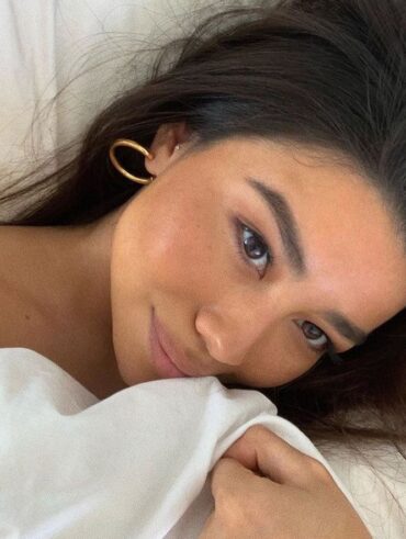 Mulher de pele clara, com cabelo preto e acessórios em dourado