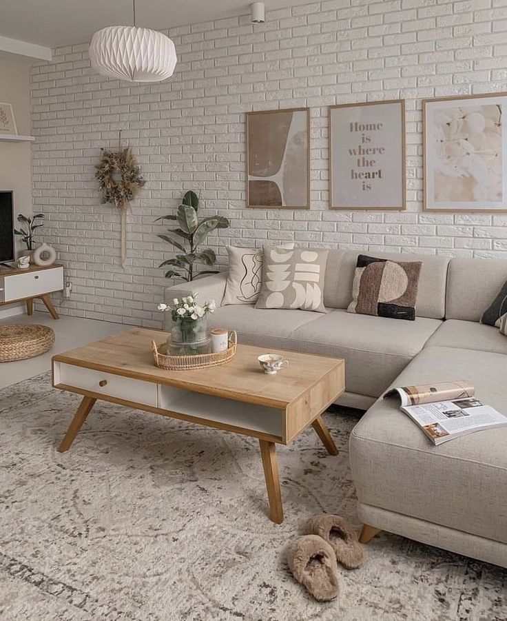 Sala em tons neutros com parede de tijolinhos e quadros