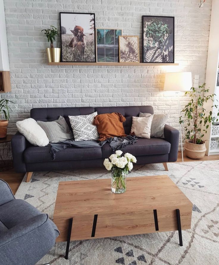 Sala com parede de tijolinhos, quadros, sofás cinza escuro