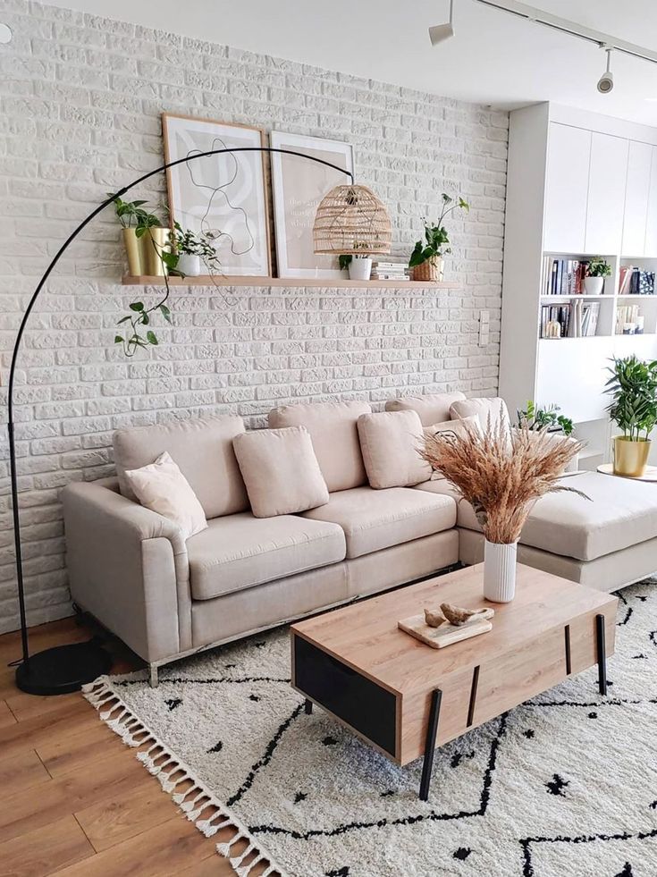 Sala com parede de tijolinhos, sofá em tom rosé e luminária de piso
