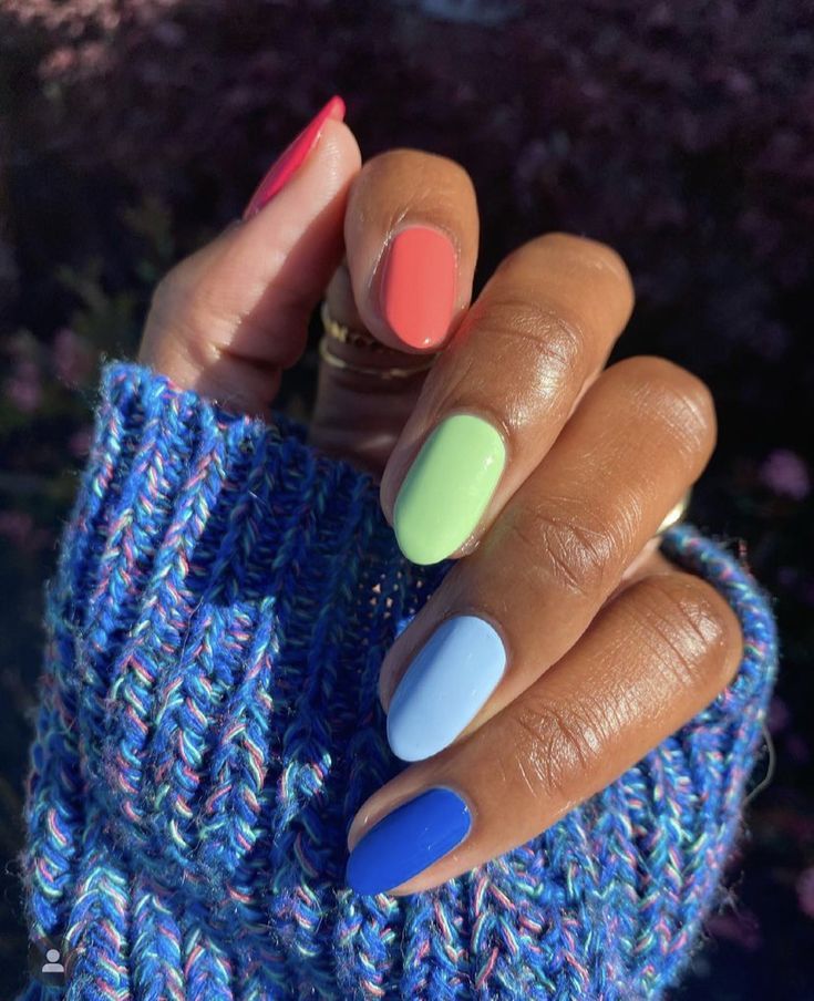Mão de pele preta, com unhas amendoadas com cores diferentes