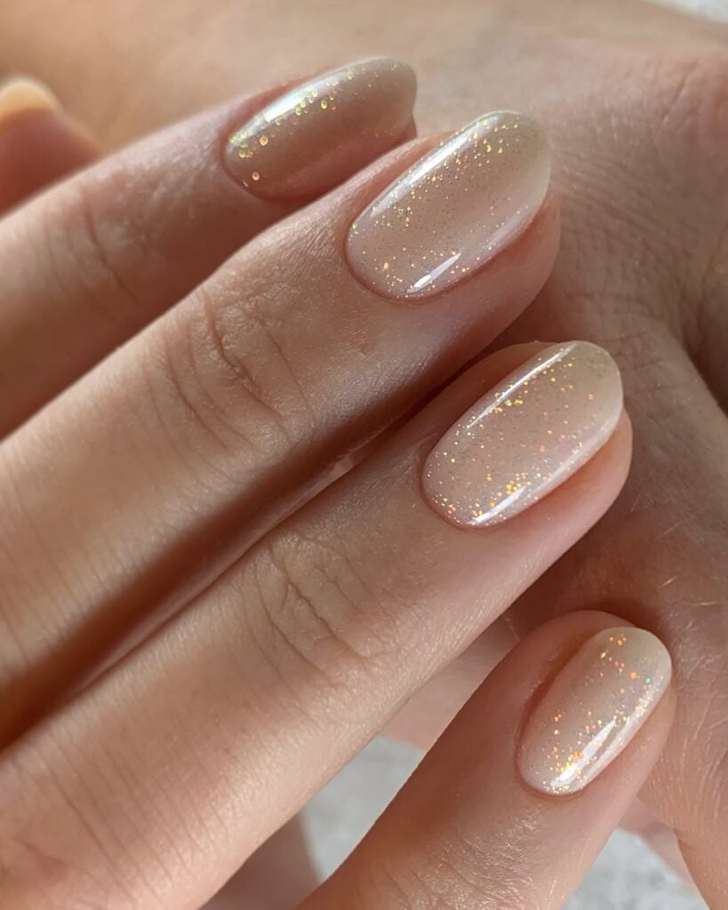 Mão de pele clara, com unha nude amendoada com top coat de brilho