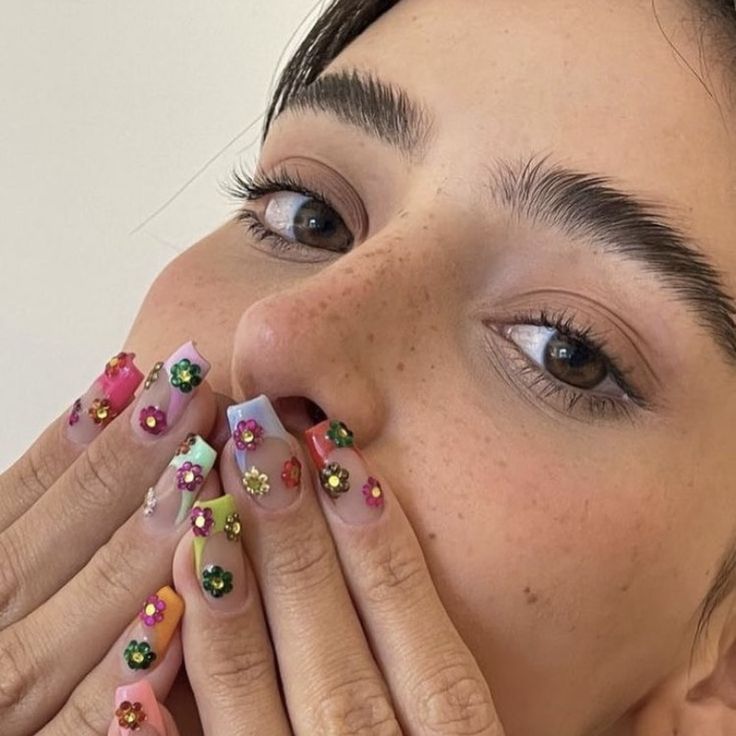 Lívia Nunes com unhas quadradas, com francesinha colorida e flores coloridas de strass