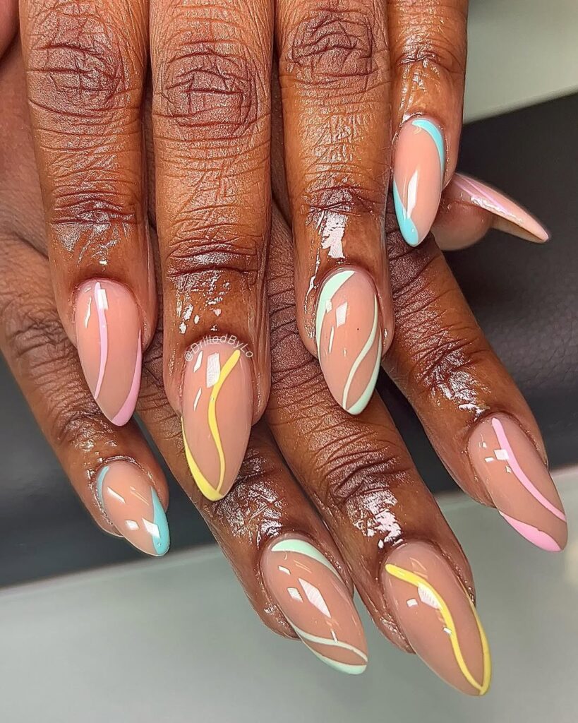 Mãos de pele preta, com unha amendoada nude, com linhas fluidas em tons pastel