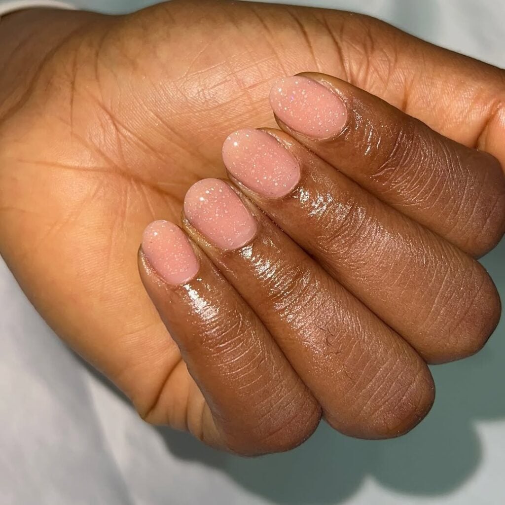 Mão de pele preta, com unha nude com top coat de brilho