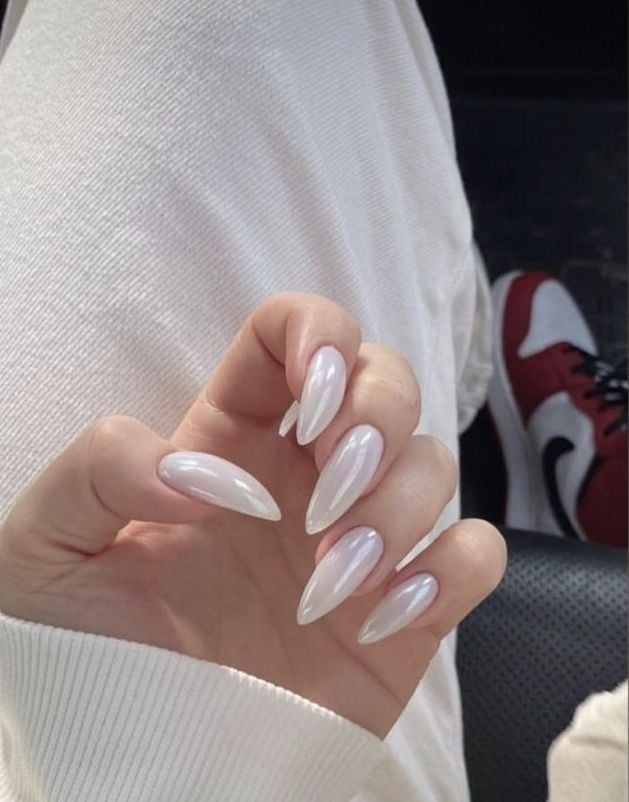 Mão de pele clara, com unha stiletto clara cintilante