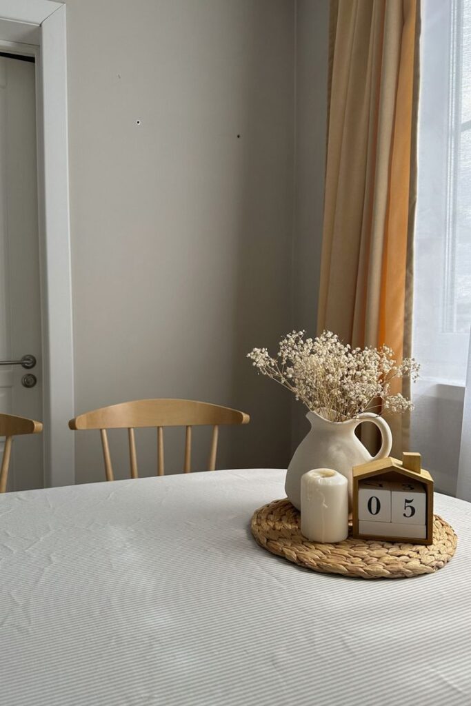 Mesa com toalha branca, calendário e arranjo de florzinhas brancas