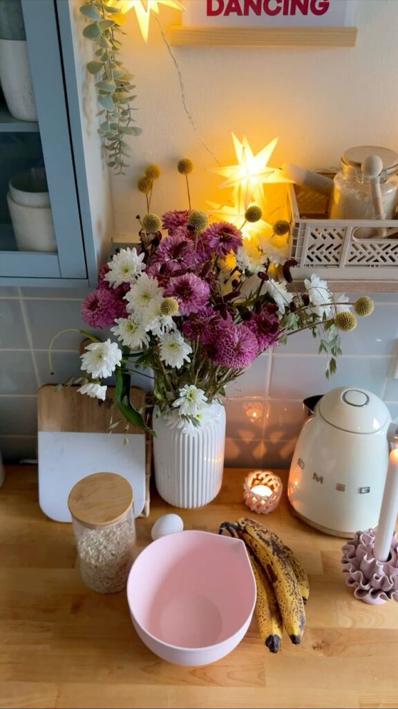 Bancada de cozinha com cafeteira e vaso de flores rosas e brancas