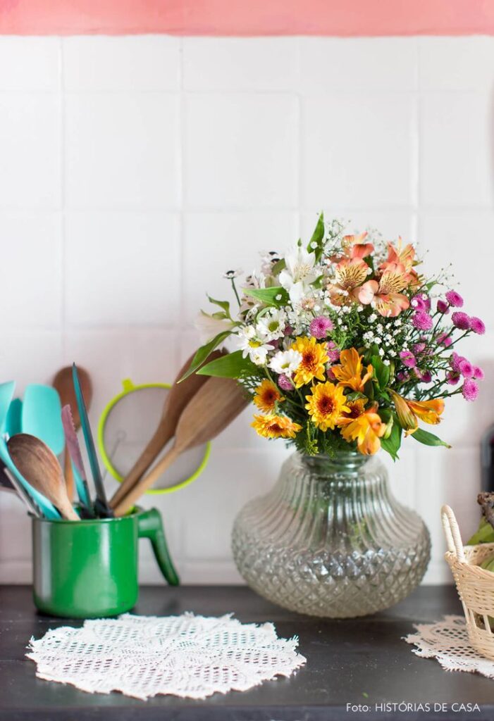 Bancada de cozinha com guardanapo de crochê, vaso de vidro com flores coloridas