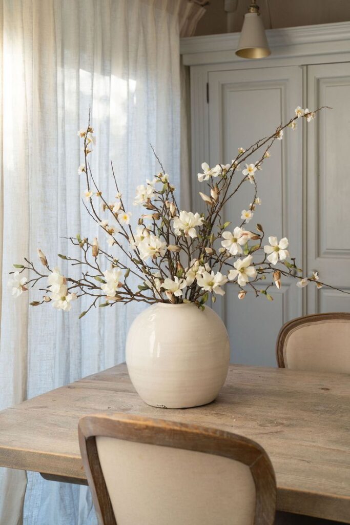 Mesa de madeira com vaso branco com flores brancas