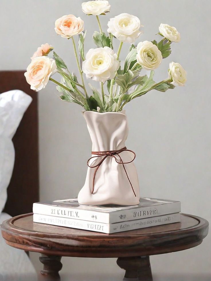 Mesa de cabeceira redonda de madeira com livros e arranjo de flores
