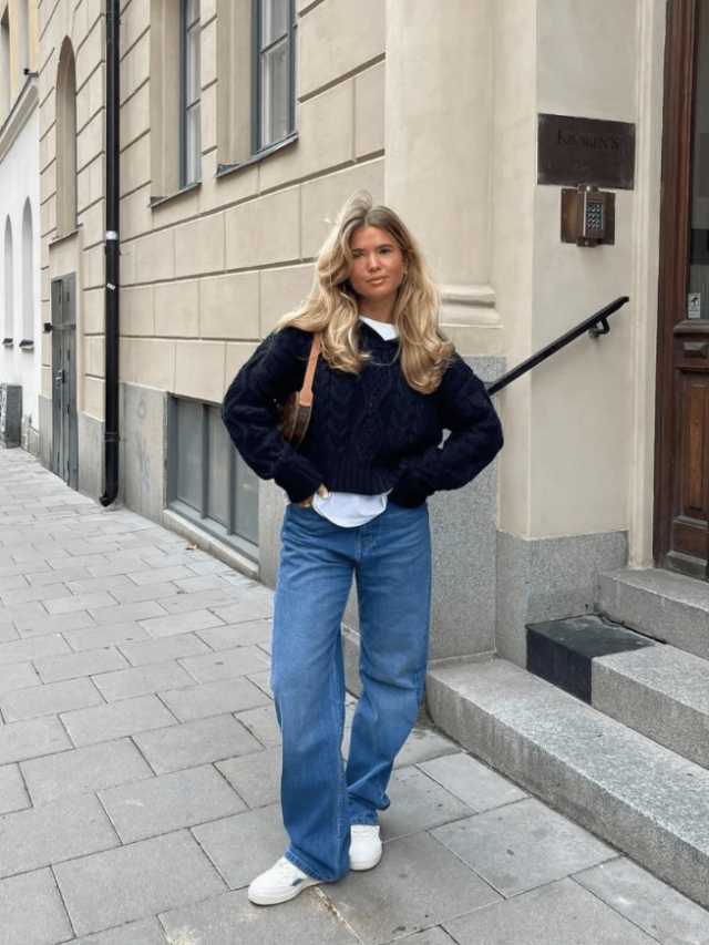 Matilda Djerf com cabelo loiro, suéter azul marinho, calça jeans e tênis branco
