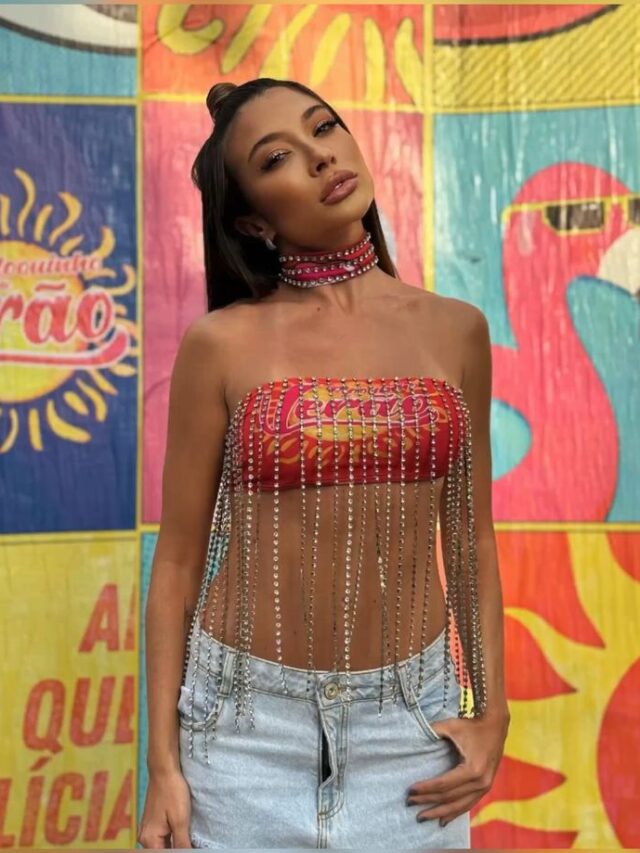 Mulher de pele média, com cabelo escuro preso e abadá em formato de top com fitilhos