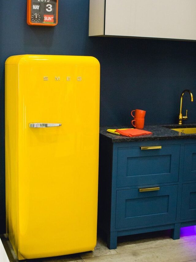 Cozinha com armários e parede azul-escuro com geladeira retrô amarela