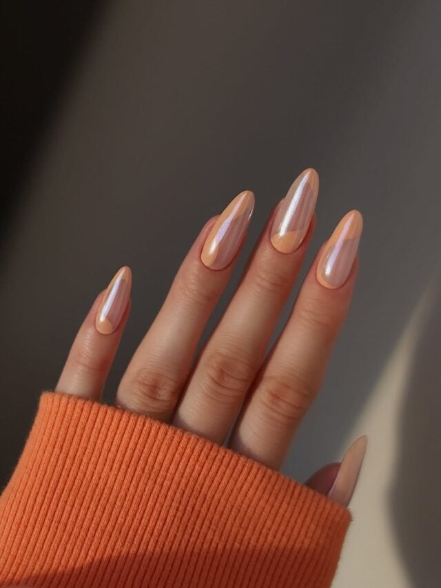 Mãos de pele branca, com unha longa e amendoada e esmalte laranja peach fuzz e nail art de traços fluidos e glazed donut nails