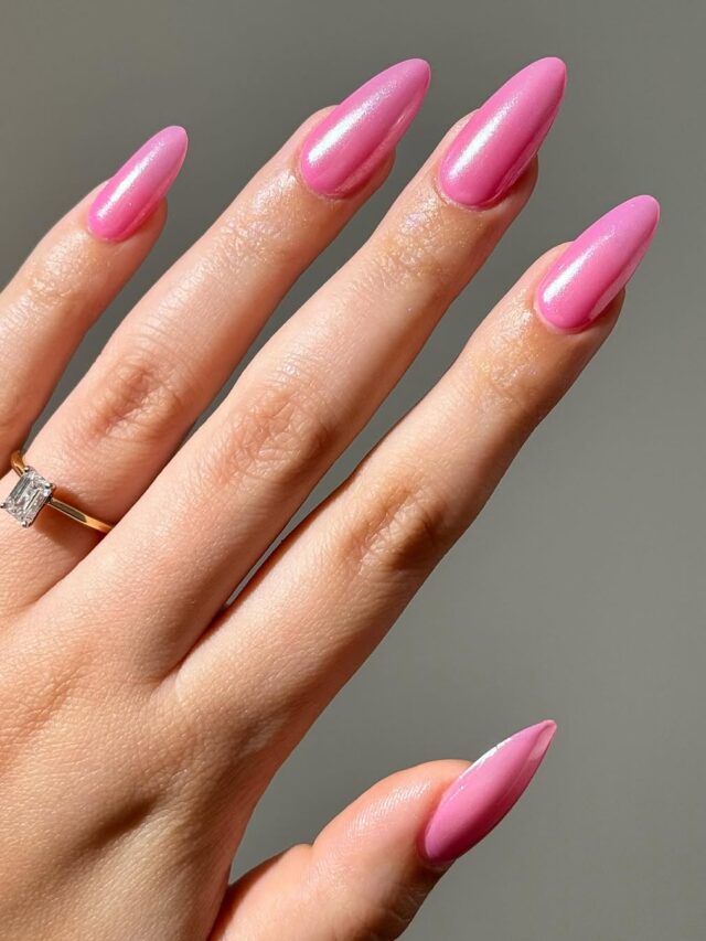 Mão de pele clara, com anel em dourado e unha amendoada rosa com acabamento jelly e glaze