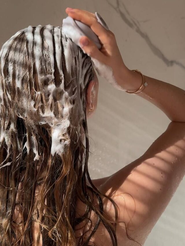 Mulher de pele clara, lavando o cabelo com escova
