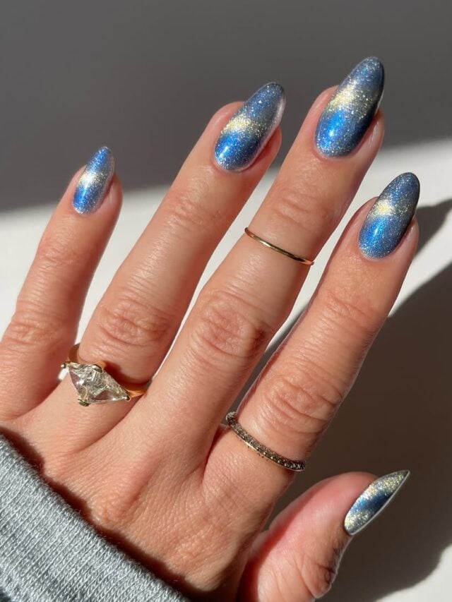 Mão de pele clara, com anéis em dourado e unha amendoada azul magnética