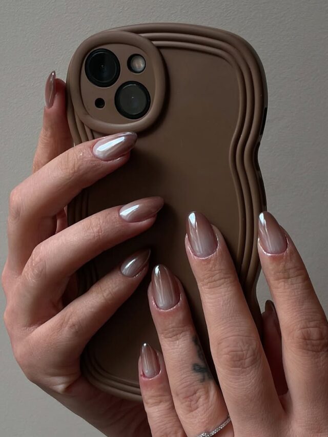 Mão de pele clara, com anel brilhodo e unha amendoada ombré com efeito glazed donut