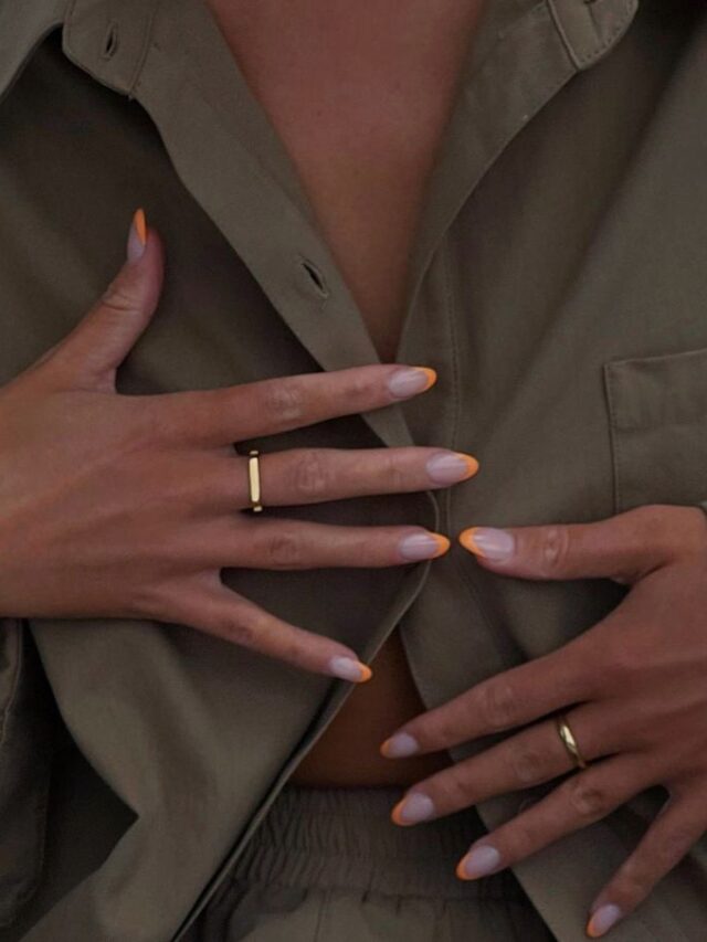foto de tronco de uma mulher jovem e magra com pele clara. Ela usa roupa verde e tem unhas lilás com francesinhas laranjas.