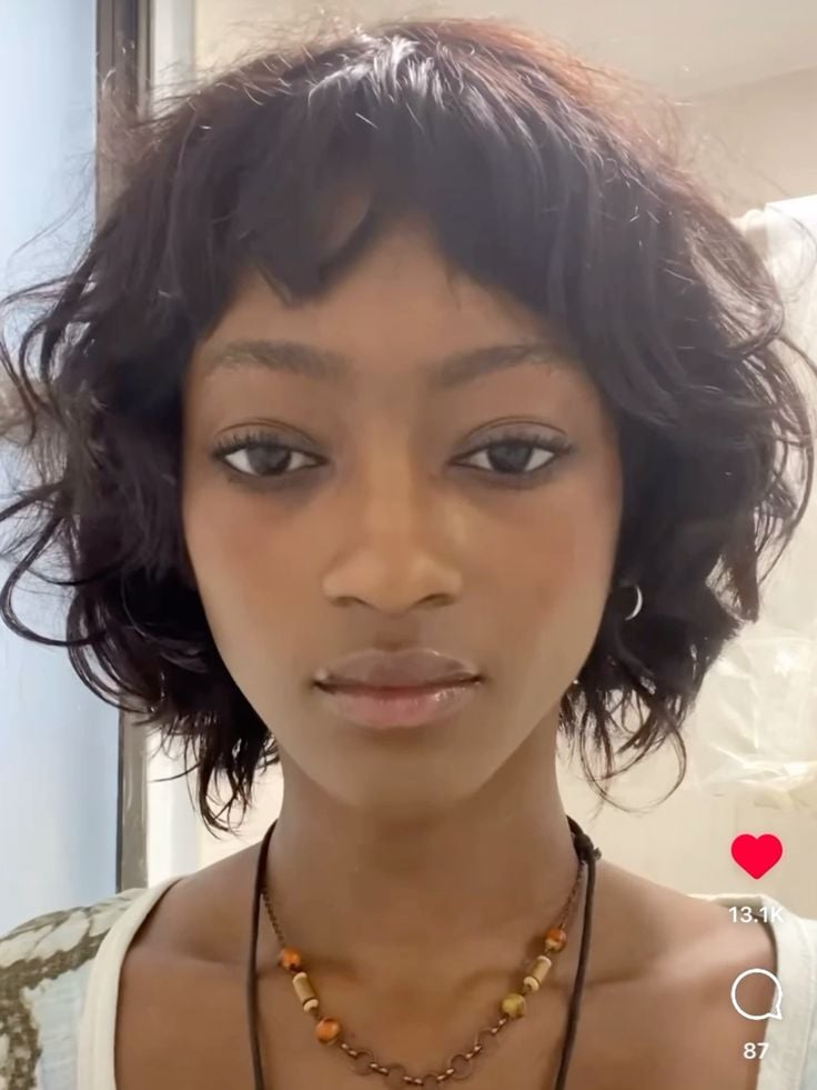 Mulher negra com cabelo castanho, curto e em camadas com franja
