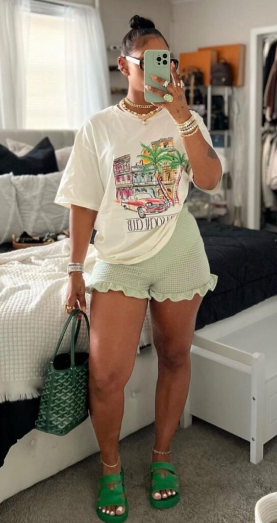 Mulher jovem em foto na frente do espelho. Ela usa blusa, bermuda, sandália e bolsa.