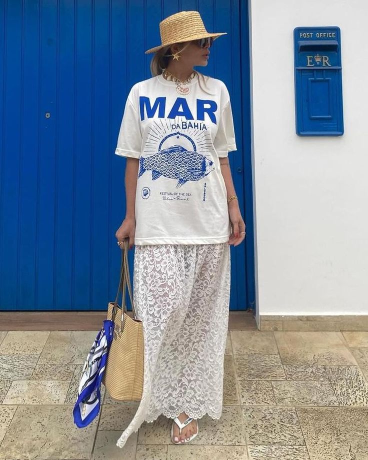 Mulher jovem e magra. Ela usa t-shirt com estampa e saia longa de renda.