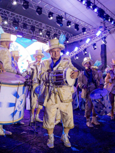 Bateria de escola de samba com homens vestidos de branco e dourado