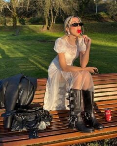 Mulher de pele clara, com vestido branco rendado e biker boots