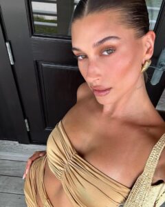 Hailey Bieber, com conjunto bege e blonzing makeup