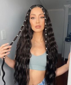 Mulher de pele clara, com top cinza, cabelo escuro com ondas