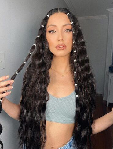 Mulher de pele clara, com top cinza, cabelo escuro com ondas