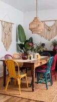 Espaço com mesa de madeira com gavetas, e cadeiras em amarelo, azul e vermelho