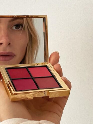 Mulher de pele clara e cabelo loiro, segurando uma paleta de blush dourada