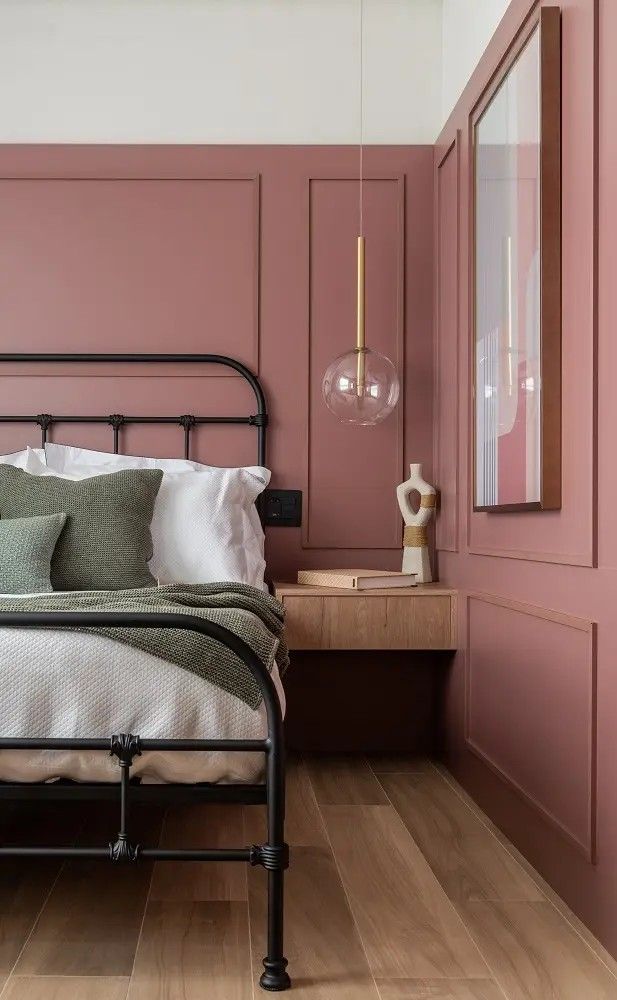Quarto com paredes rosa-queimado, cama de ferro e pendente de vidro
