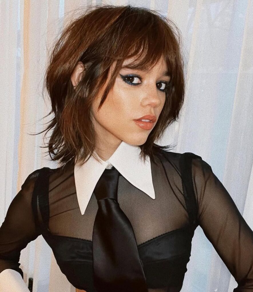 Jenna Ortega, com look preto e branco e cabelo com corte choppy bob